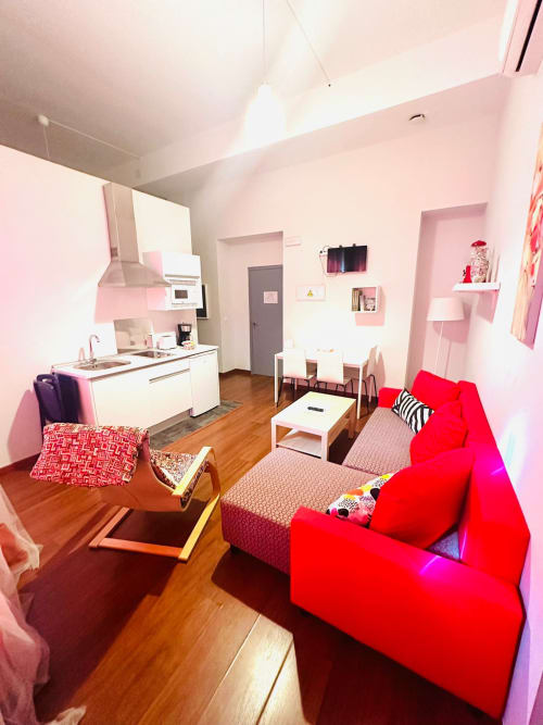 Apartamento rosa y rojo en Gestyp-AT Mérida con cocina, sala de estar, pisos de madera y muebles modernos