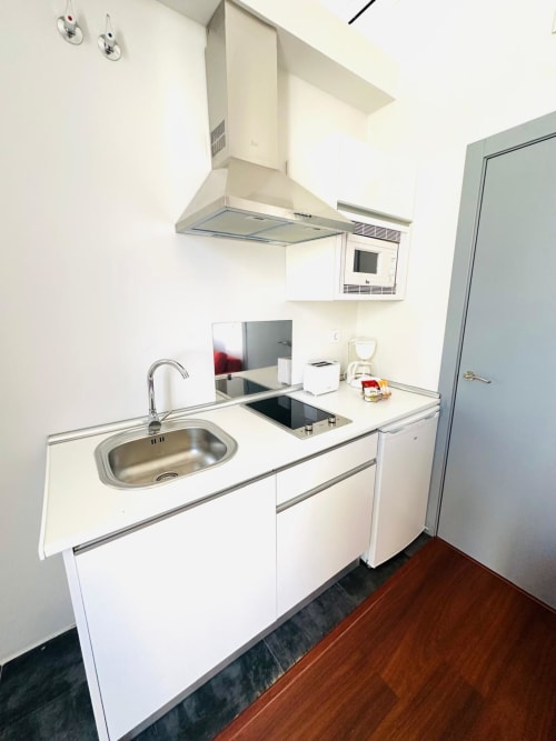 Cocina compacta con fregadero, estufa y campana extractora en apartamento Gestyp-AT, Mérida