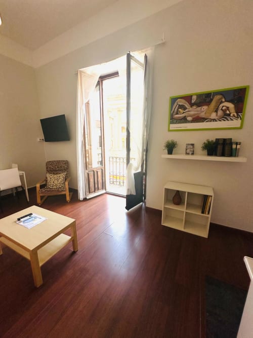 Moderna sala de estar en Mérida con pisos de madera, acceso a balcón, obras de arte y mobiliario contemporáneo