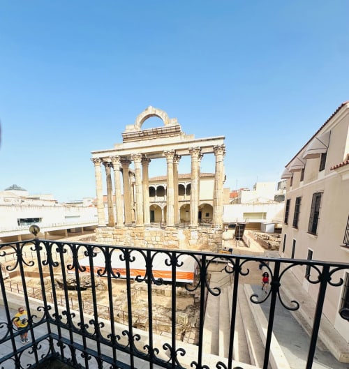 Vista de ruinas del templo romano antiguo desde el balcón del apartamento Gestyp-AT en Mérida, España, con barandilla de hierro ornamental