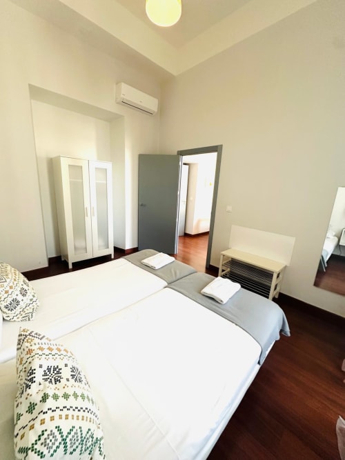 Habitación limpia de apartamento en Mérida con camas gemelas, armario blanco, aire acondicionado y pisos de madera