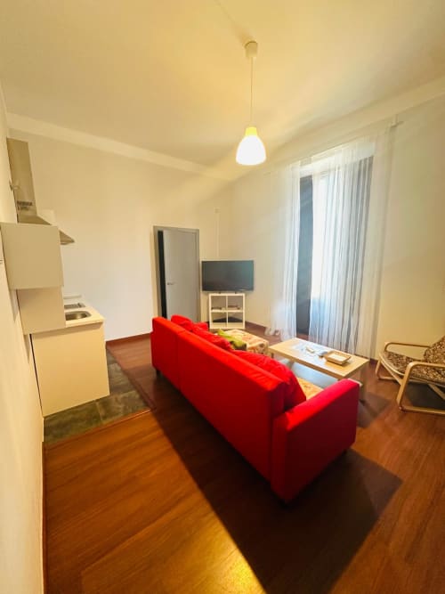 Apartamento luminoso en Mérida con sofá rojo, cocineta, televisión y pisos de madera