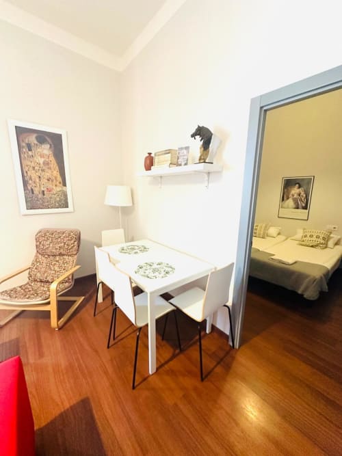 Luminosa sala de estar con mesa de comedor, sillón acogedor y vista del dormitorio en hotel de Mérida