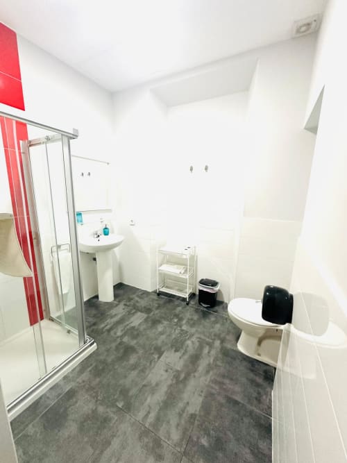 Baño moderno en apartamento de Mérida con ducha, inodoro, lavamanos de pedestal y piso de azulejos grises