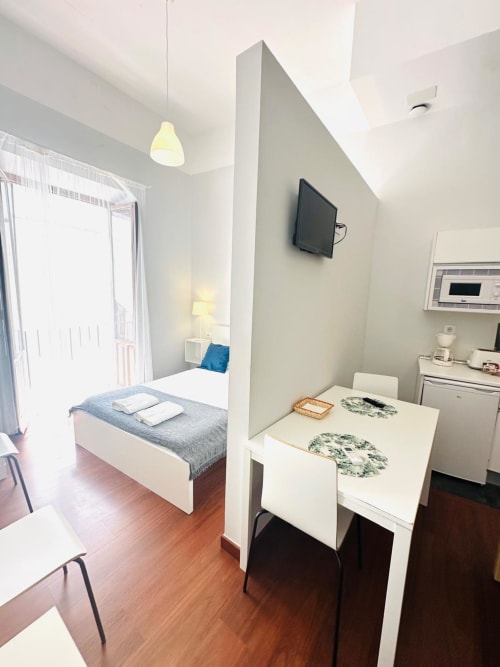 Moderno apartamento estudio en Mérida con cama, comedor, cocina y TV en la pared