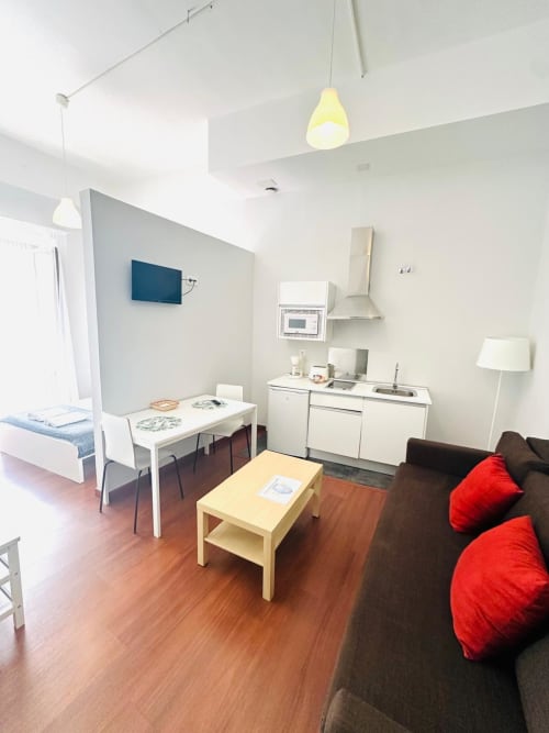 Moderno estudio en Mérida con cocineta, comedor, sofá marrón con cojines rojos y pisos de madera