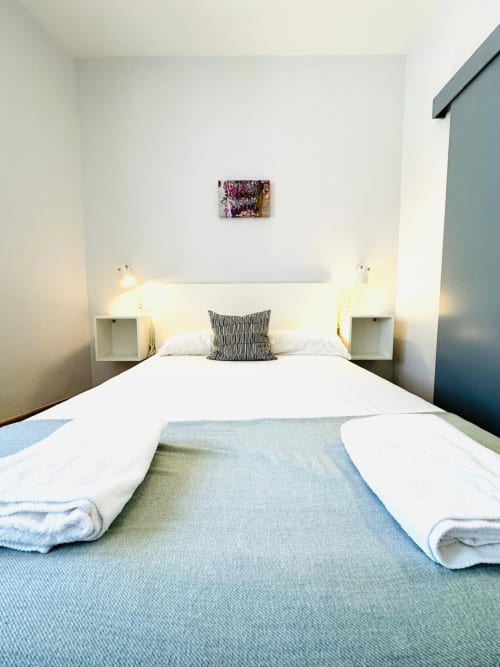 Dormitorio moderno en apartamento Gestyp-AT en Mérida con cama queen, ropa de cama blanca, almohada a rayas y decoración minimalista