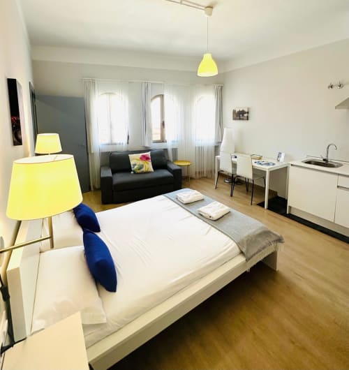 Moderno estudio en Gestyp-AT, Mérida, con cama, sofá negro, iluminación amarilla y cocina americana