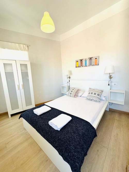 Dormitorio moderno en apartamento Gestyp-AT en Mérida con cama blanca, camino negro y decoración minimalista