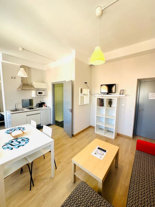 Apartamento moderno en Mérida con cocina abierta, mesa de comedor, pisos de madera y lámpara colgante amarillo brillante