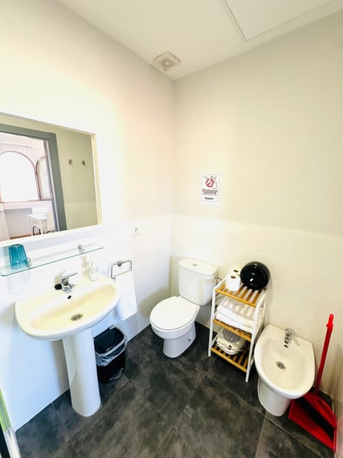 Baño limpio en apartamento de Mérida con lavabo, inodoro, bidé y estantería de almacenamiento