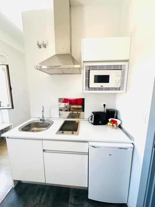 Cocina moderna blanca en apartamento de Mérida con estufa, fregadero, microondas y refrigerador