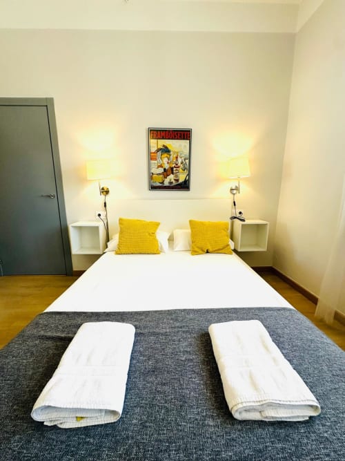 Dormitorio moderno del apartamento Gestyp-AT en Mérida con almohadas amarillas, camas gemelas y póster vintage