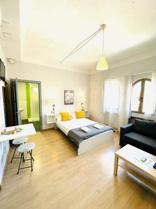 Moderno estudio en Mérida con cama matrimonial, detalles amarillos, cocina equipada y ventanas arqueadas