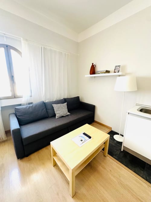 Sala de estar moderna en Mérida con sofá negro, mesa de madera y ventanas luminosas con cortinas blancas