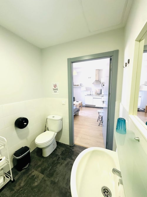 Baño moderno en apartamento de Mérida con inodoro, bañera y vista hacia la zona de cocina