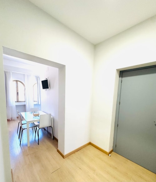 Elegante entrada de apartamento moderno en Gestyp-AT en Mérida con zona de comedor visible a través de la puerta abierta, piso de madera y toque de verde