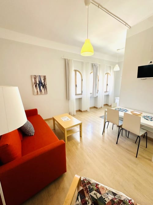 Moderno apartamento en Mérida con sofá rojo brillante, lámpara colgante amarilla, muebles de madera y zona de oficina