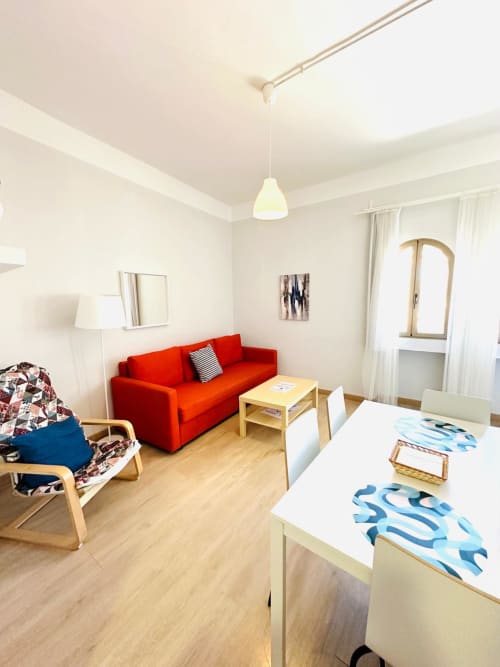 Luminoso apartamento en Mérida con sofá rojo, muebles de madera e iluminación colgante moderna