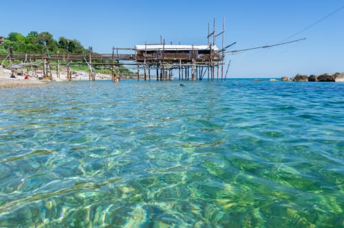 Agua turquesa cristalina con muelle de madera en la propiedad frente al mar Casale 905 en Crecchio, Italia