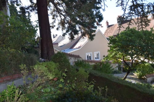 Le Fassardy B&B in Châteauroux framed by tall trees and lush greenery surrounding the cottage.