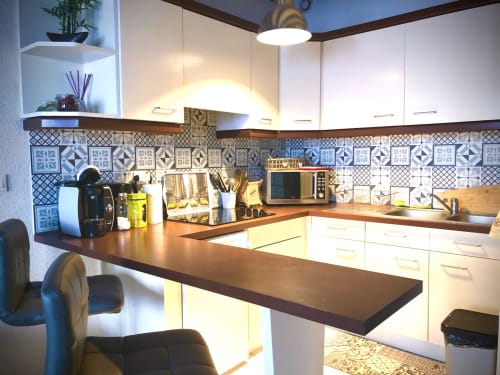 Modern kitchen in Le Charmant Zola apartment, Troyes, with white cabinetry, patterned tile backsplash, and dark wood