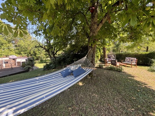 Striped hammock under large tree in Maison Mûrier garden, Fayssac with seating area