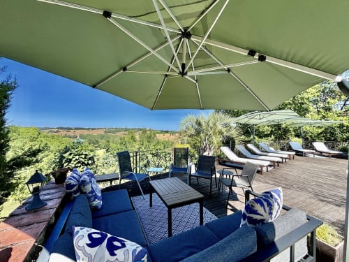 Maison Mûrier terrace in Fayssac with green umbrellas, lounge chairs, and countryside views