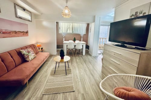 Salón moderno de villa en Baiona con sofá coral, TV, comedor y acceso a balcón con vistas al mar