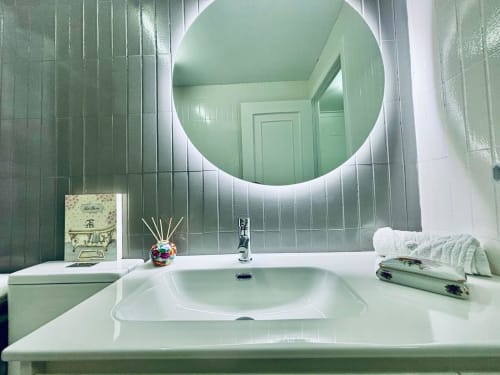 Moderno lavamanos con espejo circular iluminado en Villa Natercia, Baiona