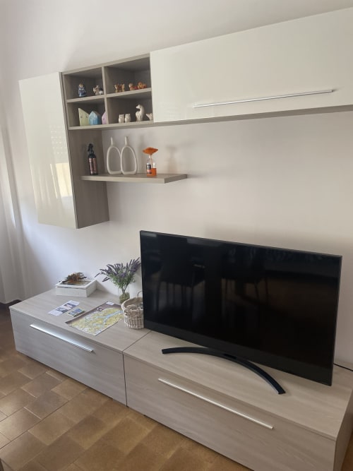 Moderno mobile intrattenimento bianco con TV schermo piatto e ripiani a parete nell'appartamento Varenna