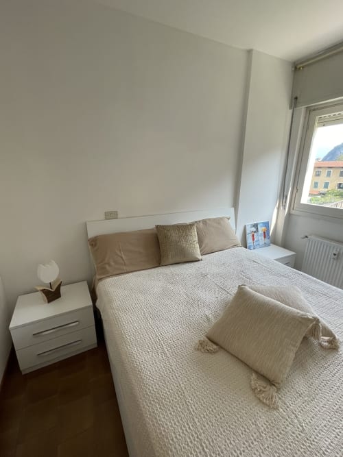 Luminosa camera moderna a Varenna by Foot con letto bianco, comodino, finestra con vista montagna e arredamento neutro