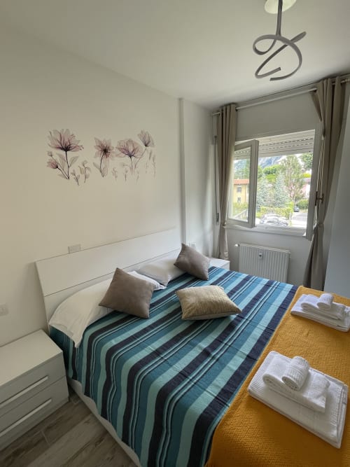 Bright bedroom at Varenna by Foot with striped bedding, white headboard, floral wall art, and mountain view from window