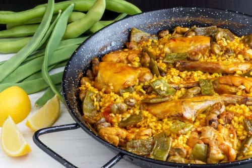 Paella con pollo y judías verdes servida en Apartamentos Burriana, Burriana España, con gajos de limón
