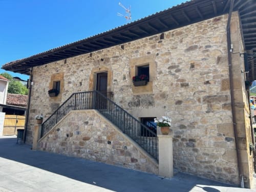 Edificio de piedra Las Llaviadas con vistas a la montaña en Ortiguero de Cabrales, con escalera exterior y estilo rústico