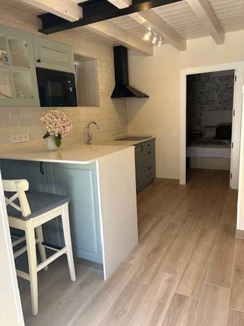 Cocina moderna en apartamento Las Llaviadas con isla, azulejos crema, campana negra y piso tipo madera.