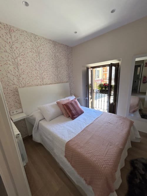 Dormitorio moderno en Las Llaviadas con cama matrimonial, papel tapiz floral y balcón con vistas a las montañas de Cabrales