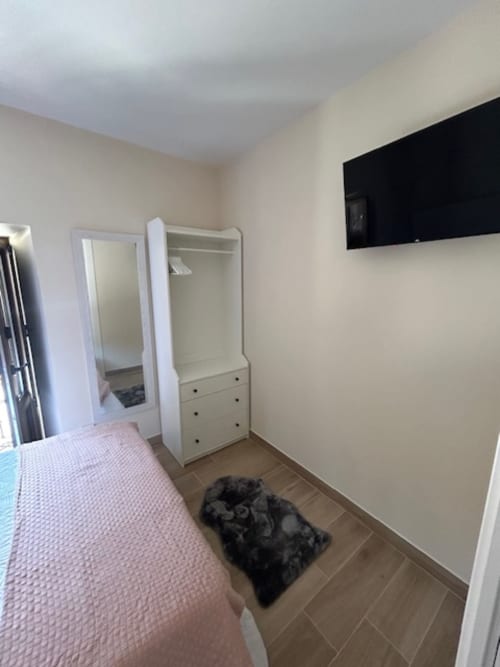 Moderno dormitorio de apartamento en Las Llaviadas con armario blanco, cama rosa, TV mural y vistas a las montañas de Cabrales