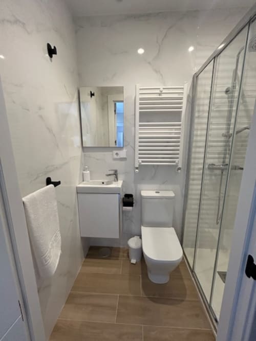 Baño moderno del apartamento Las Llaviadas en Ortiguero de Cabrales con paredes de mármol, ducha y toallero climatizado