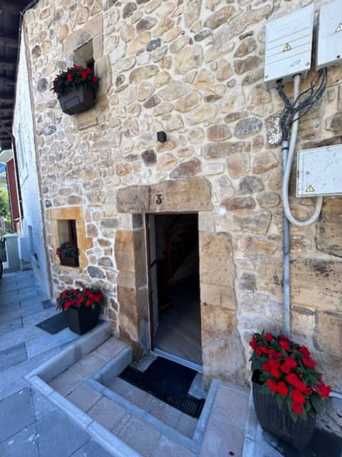 Entrada de casita de piedra en Las Llaviadas, Ortiguero de Cabrales, adornada con flores de Pascua rojo