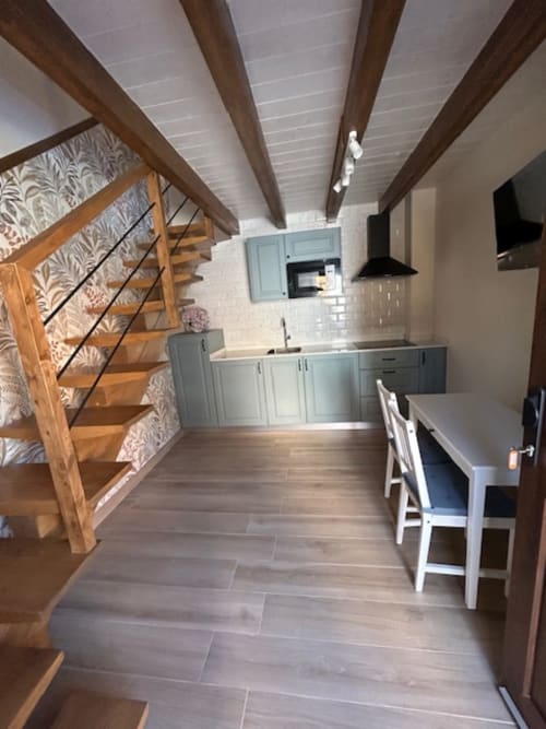 Moderno loft en Las Llaviadas con escaleras de madera, cocina azul, vigas vistas y comedor en Cabrales