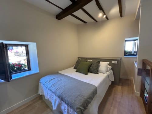 Dormitorio moderno en el apartamento Las Llaviadas de Ortiguero de Cabrales con cama de matrimonio, vigas vistas, vistas a la montaña y