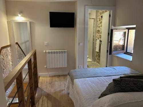 Moderna habitación con camas gemelas, vistas a la montaña, baño y TV en pared en Las Llaviadas, Cabrales