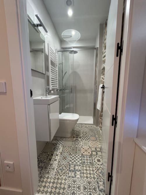 Cuarto de baño moderno en el apartamento Las Llaviadas en Ortiguero de Cabrales con suelo de azulejos con patrón y ducha de cristal