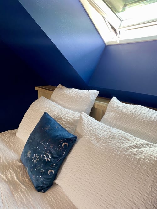 Chambre cosy à Lady Jule B&B avec plafond mansardé bleu, lucarne, tête de lit en bois, literie matelassée blanche