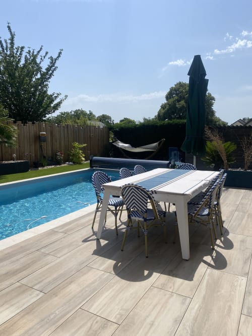 Espace de restauration au bord de la piscine de Lady Jule Chambres d'hôtes avec chaises bleues rayées, table et piscine