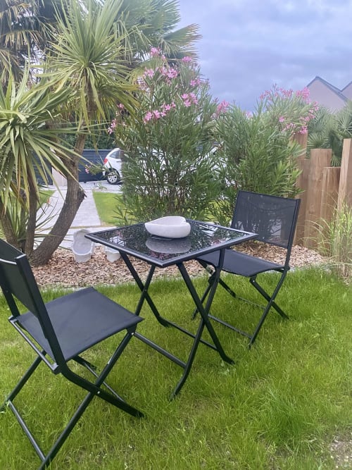 Coin détente extérieur du gîte Lady Jule avec chaises noires, table et plantes fleuries roses à Sainte-Luce-sur-Loire