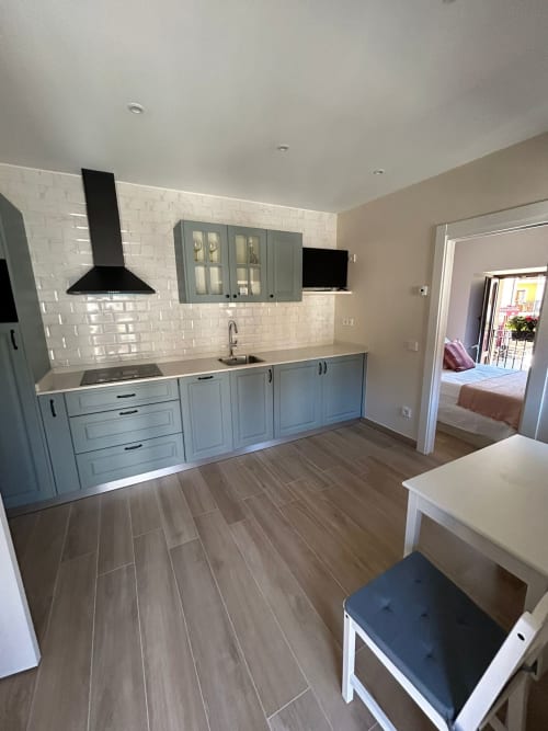Cocina moderna con gabinetes azules, azulejos tipo metro blancos y pisos de madera en el apartamento Las Llaviadas en Ortiguero