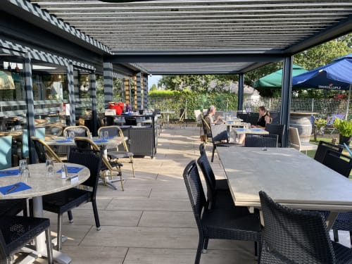 Terrasse de restauration extérieure du Lady Jule B&B à Sainte-Luce-sur-Loire avec tables, chaises noires et pergola rétractable