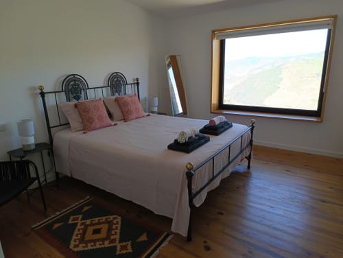 Quarto espaçoso com estrutura de cama em metal, vistas do vale fluvial através de ampla janela, pisos de madeira e comodidades modernas na Quinta
